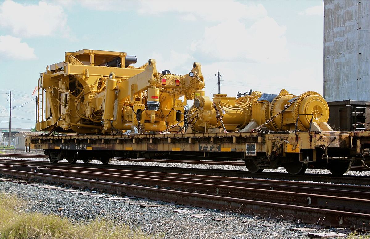 Heavy yellow industrial equipment on a flatcar at the Port of Houston docks, waiting for export